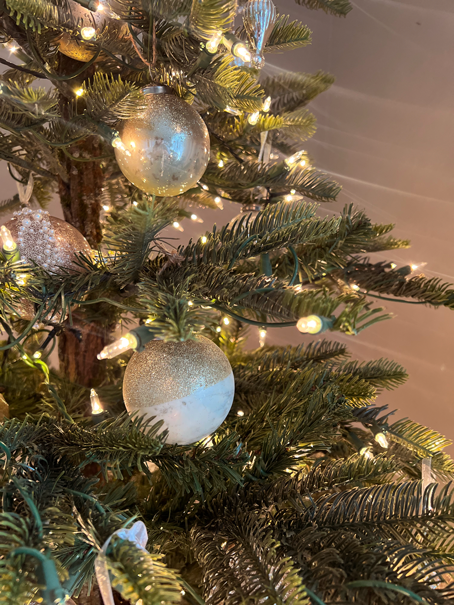 Christmas tree with warm glow of twinkle lights, vintage glass bulbs, real tree bark trunk