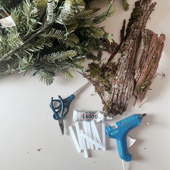 Materials for Christmas tree bark project using tree bark, hot glue, a hot glue gun, and an artificial Christmas tree.