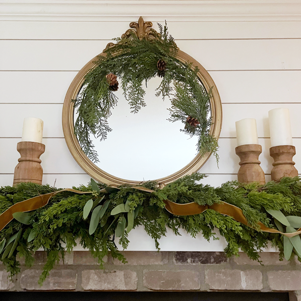 Rub'-N-Buff Mirror Makeover. European Muted Gold mirror over Christmas fireplace mantel with greenery and wooden candle sticks