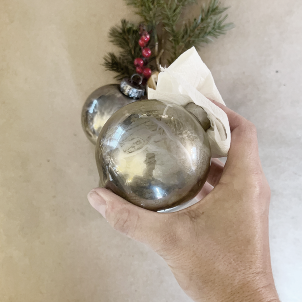 reflective metallic ornament in hand. Shaking and rotating the paint inside the DIY project. 