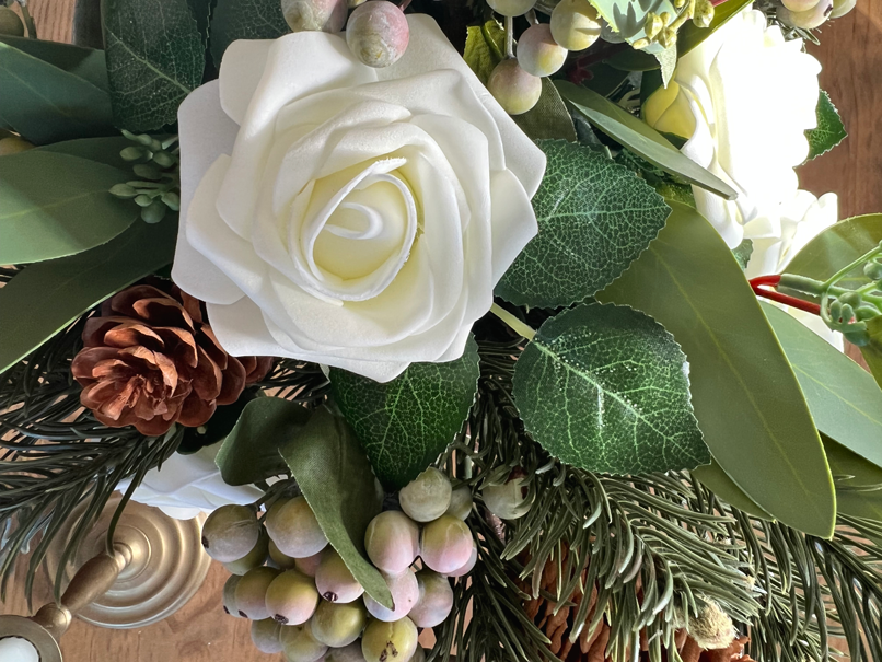 Close up view of winter flower bouquet made of green eucalyptus, green pine, white roses, and green-blue frosted berries.