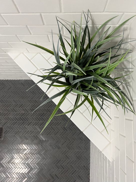 Bathroom shower with black herringbone floor tile and white subway tile.