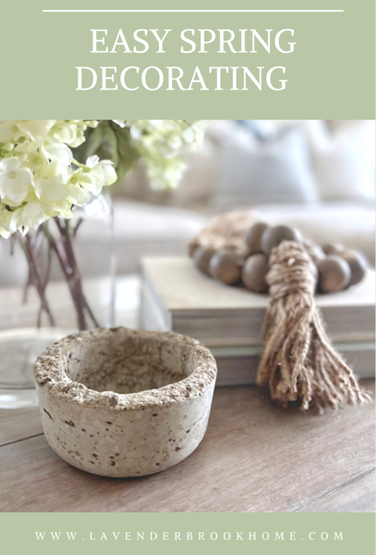 Easy spring decorating ideas photo of hydrangeas in a glass vase with books, wooden bead garland and a small concrete bowl.