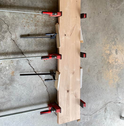 Clamps holding two boards together as they allow for glue to dry of for the ten inch board.