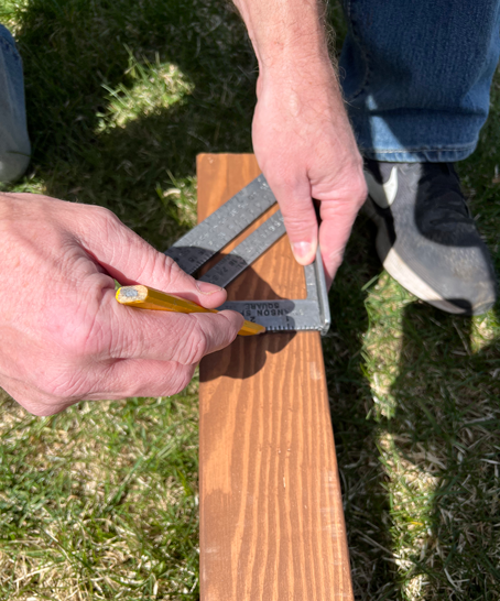 Using a square tool to draw and straight and level line for attaching the beam to the post. 