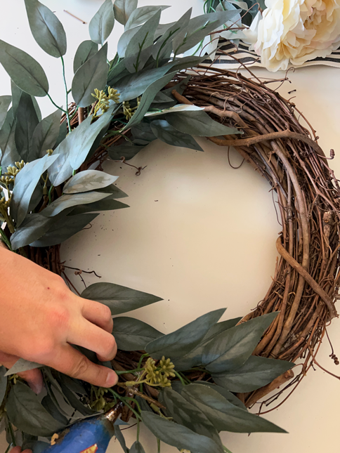 Wreath with eucalyptus stems on 2/3 of a grapevine wreath base. 