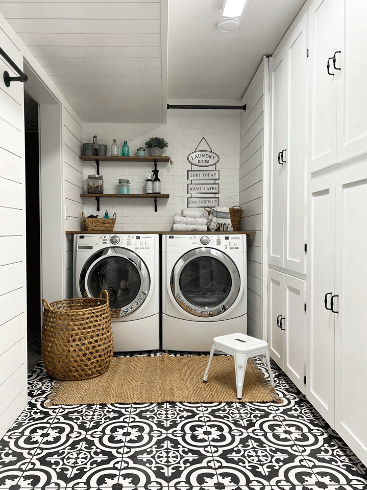 Laundry room with built in storage, bar height folding table, drying racks for hanging or hang drying laundry, dirty laundry metal storage baskets, and decorated with woven baskets, a laundry room sign, a woven rug, and patterned tile to compliment the wood and white board and batten and shiplap walls.