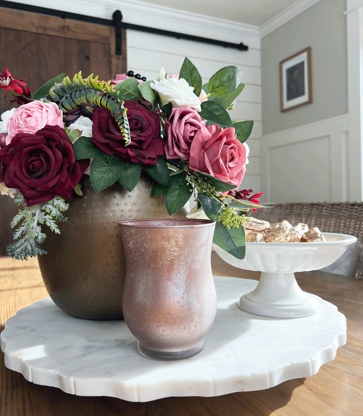 DIY Mercury Glass Votives: A candle holder in shimmery gold, silver, metallic pink, and copper colors. Candles glow from within and a rich colored burgundy and pink bouquet in a gold vase sits in the background. 